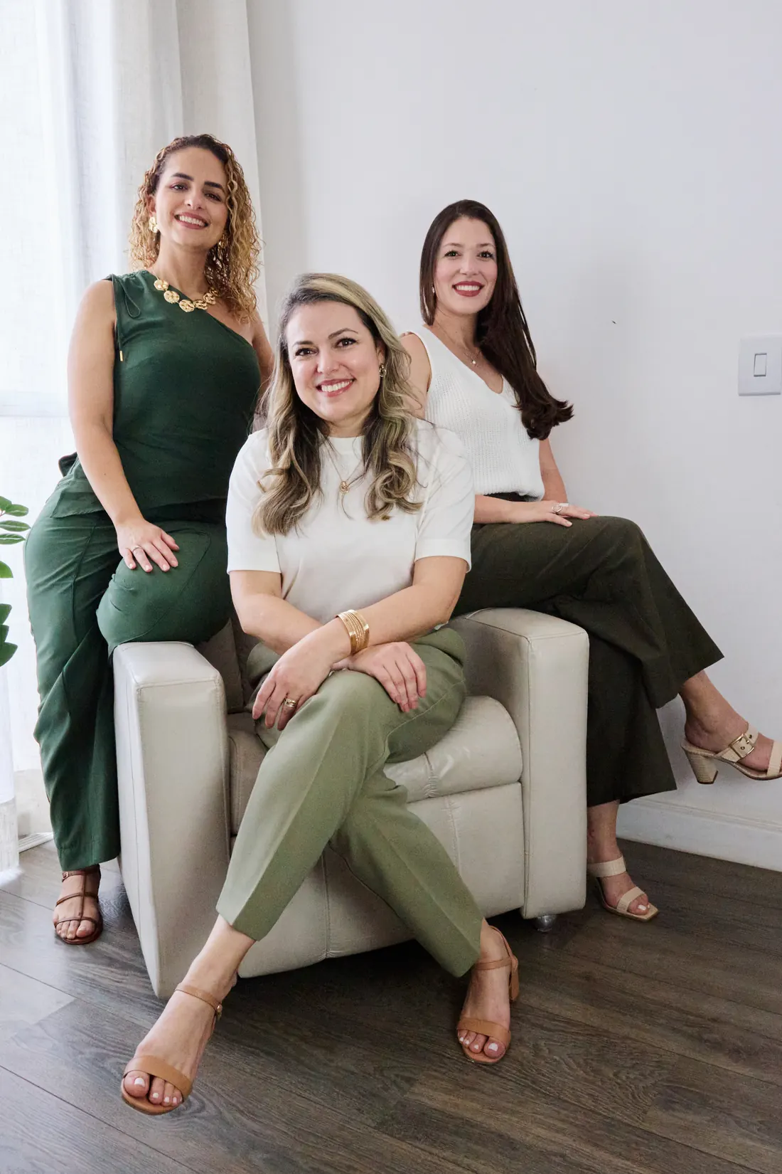 Vanessa, Adelita e Viviane, psicólogas da Pensando Bem, sentadas juntas em uma poltrona clara